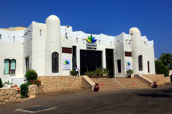 Eingang des Sharm Club Beach Resorts mit einer Person und Pflanzen davor