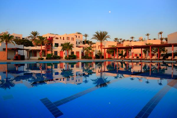 Außenpool des Sharm Club Beach Resort mit weißen Gebäuden und Palmen im Hintergrund.