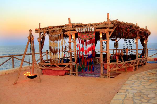 Abendstimmung am Sharm Club Beach Resort mit Blick auf das Meer und einem brennenden Feuer in einer kleinen Hütte.