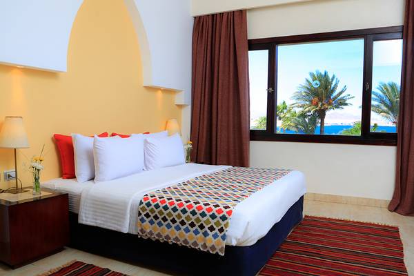 Ein Zimmer im Sharm Club Beach Resort mit Blick auf das Meer und Palmen.