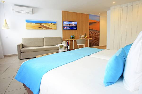 Hotelzimmer im LABRANDA Playa Bonita mit zwei Betten, Sofa, Fernseher und Dekoartikeln.
