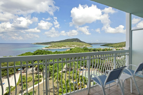 Balkon mit Meerblick im Dreams Curacao Resort, Spa & Casino mit zwei blauen Stühlen und einem Tisch.