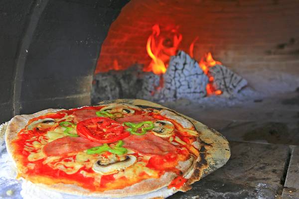 Eine Pizza mit Tomaten, Peperoni und Pilzen brät im Ofen