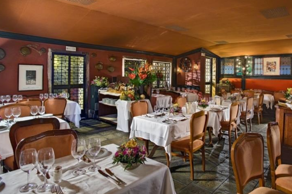 Innenansicht des Restaurants im Montecarlo Hotel mit gedeckten Tischen und Stühlen.