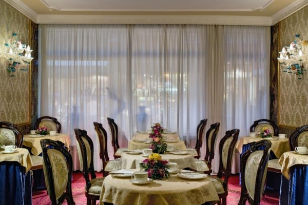 Innenansicht des Speisesaals im Hotel Montecarlo mit elegant eingerichteten Tischen und Stühlen.