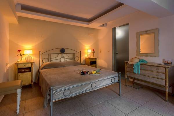 Schlafzimmer im Orpheas Resort mit Bett, Nachttischen, Spiegel und Kommode.