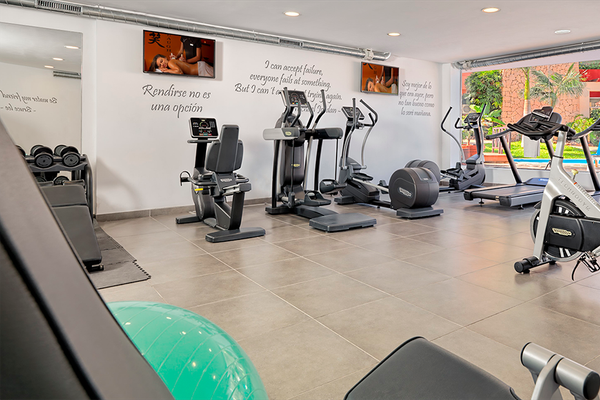 Fitnessraum im Aparthotel Allegro Isora mit verschiedenen Trainingsgeräten und einer Wand mit inspirierenden Zitaten.
