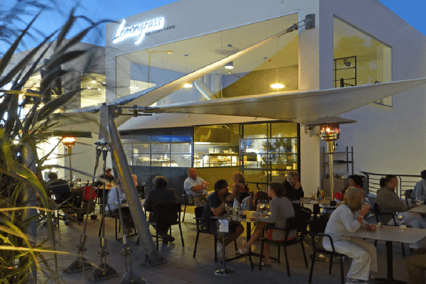 Gäste sitzen bei Tischen auf der Terrasse des Lemongrass Hotels bei Nacht