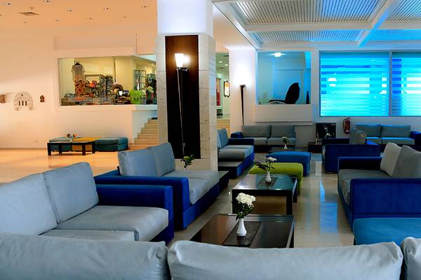 Lobby des Blue Bay Beach Resorts mit blauen Sofas, weißen Wänden und großen Fenstern.