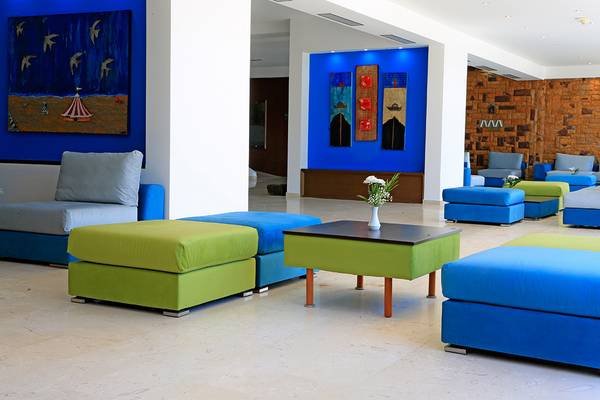 Lobby des Blue Bay Beach Resorts mit blauen und grünen Möbeln und dekorativen Gemälden.
