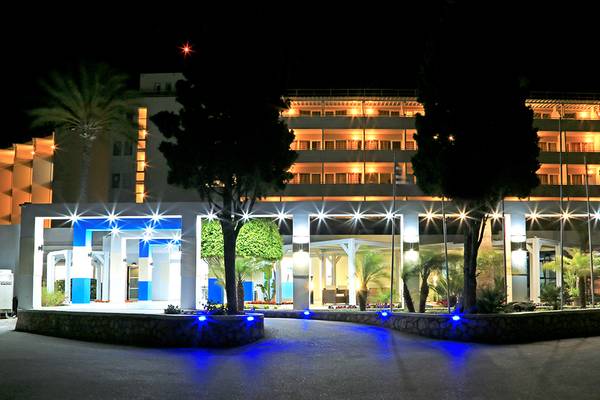 Der Eingang des Blue Bay Beach Resorts in der Nacht mit blauen Lichtern und Bäumen.