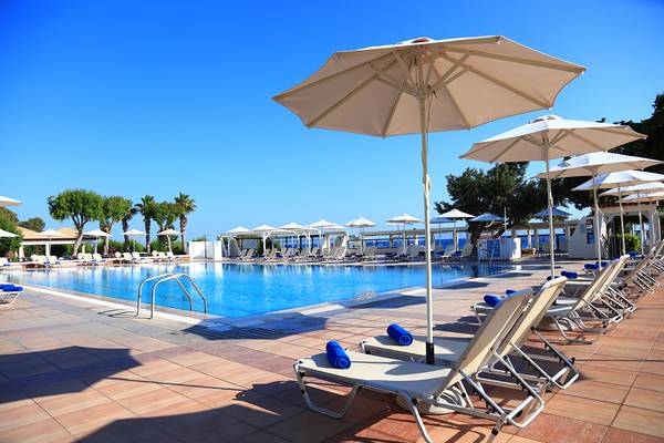 Ein Poolbereich des Blue Bay Beach Resorts mit Sonnenschirmen und Liegestühlen.