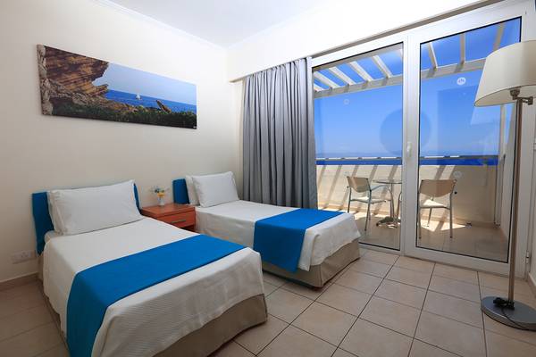 Zwei Betten mit Blick auf einen Balkon im Blue Bay Beach Resort.