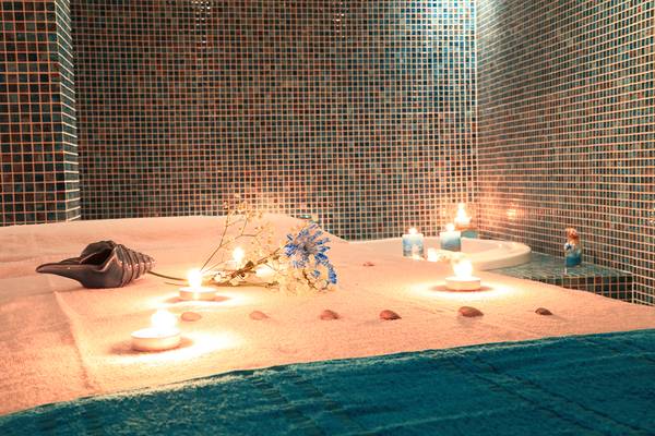 Spa-Behandlung im Blue Bay Beach Resort mit Kerzen und Blumen auf dem Bett.