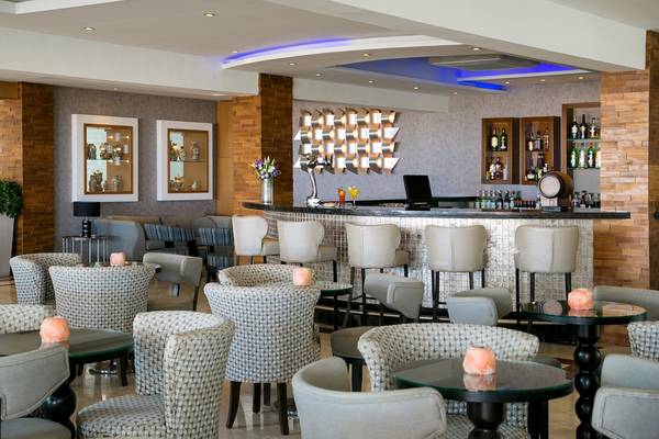 Innenbereich der Bar im Asterias Beach Hotel mit Sitzgelegenheiten und einer Theke.
