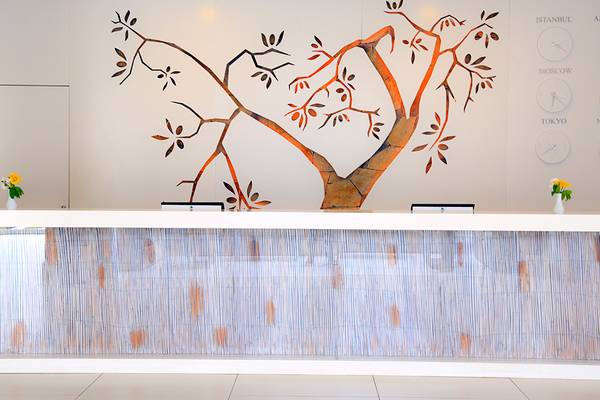 Rezeptionsbereich des Labranda TMT Bodrum mit einer Wandgestaltung, die einen Baum darstellt, und zwei Uhren, die verschiedene Städte darstellen.