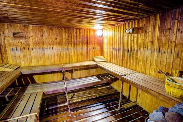 Sauna im SBH Club Paraiso Playa mit hölzernen Bänken und einer gelben Holzwanne.