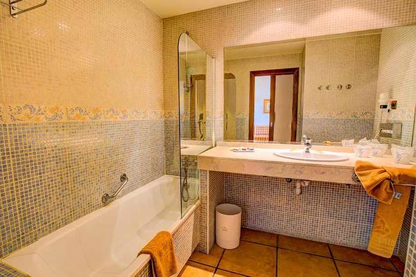 Badezimmer im SBH Club Paraiso Playa Hotel mit Badewanne, Spiegel und Waschbecken.