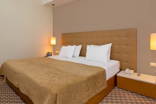 Schlafzimmer im Crystal Centro Resort mit Doppelbett, Nachttischen und Wandleuchten.