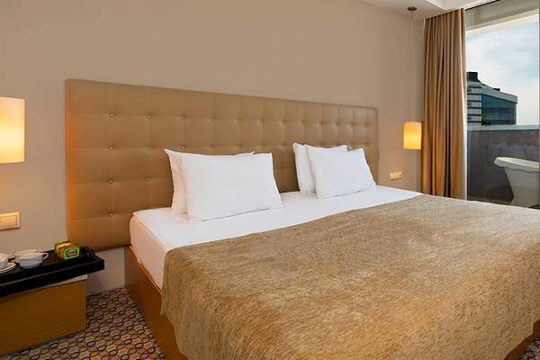 Ein Hotelzimmer im Crystal Centro Resort mit einem großen Bett, einem Balkon und Blick auf die Stadt.