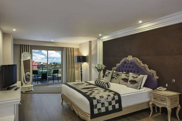 Schlafzimmer des Delphin Imperial Hotels mit großem Bett, Fernseher und Balkon
