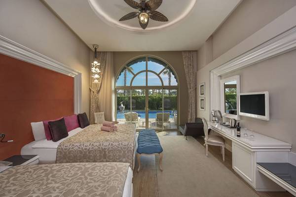 Doppelzimmer im Delphin Imperial Hotel mit zwei Betten, Blick auf den Pool und Terrasse.