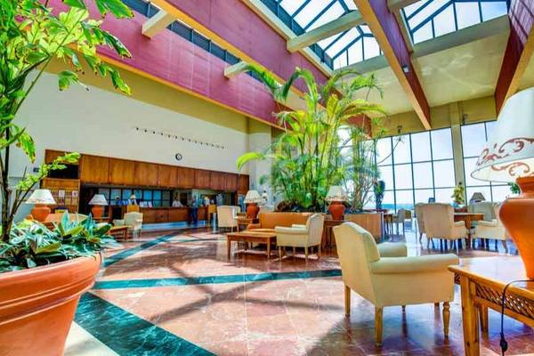 Lobby des SBH Club Paraiso Playa Hotels mit großen Pflanzen und Möbeln.