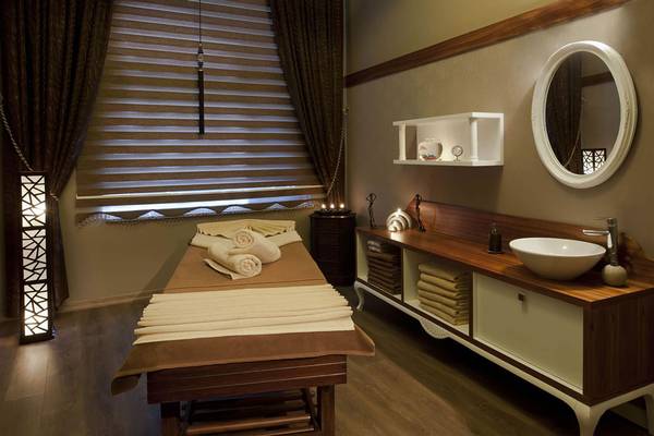 Spa-Behandlungsraum im Delphin Imperial Hotel mit Massageliege, Handtüchern und Waschbecken.