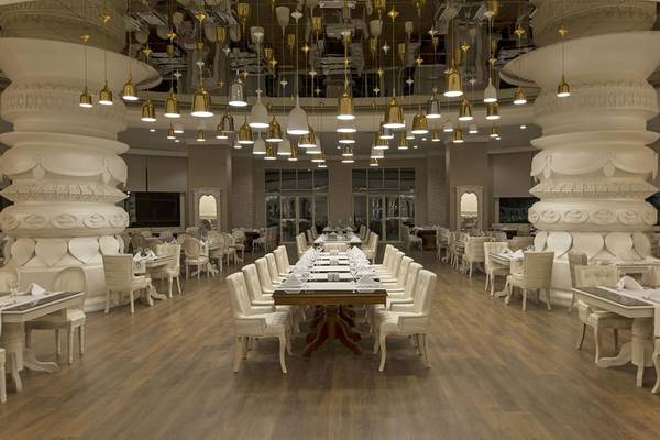 Innenansicht des Restaurants im Delphin Imperial Hotel mit weißen Säulen und hängenden Kronleuchtern.