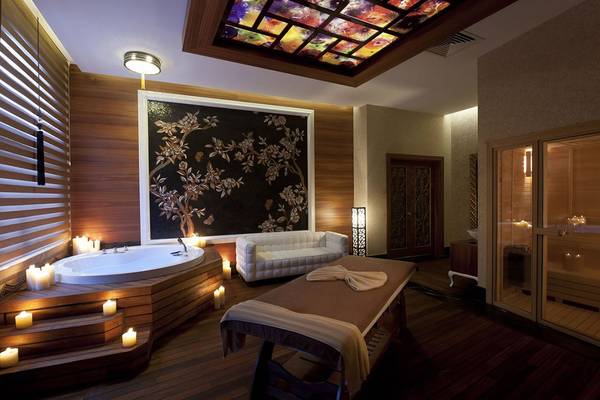 Spa-Bereich im Delphin Imperial Hotel mit Badewanne, Liege, Deko und Beleuchtung.