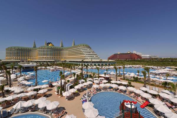 Außenansicht des Delphin Imperial Hotels mit großen Swimmingpools und vielen Sonnenschirmen.
