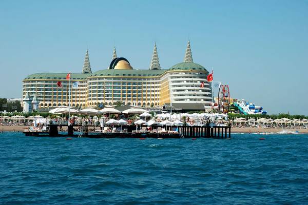 Außenansicht des Delphin Imperial Hotels am Strand mit vielen Sonnenschirmen und Wasserrutschen