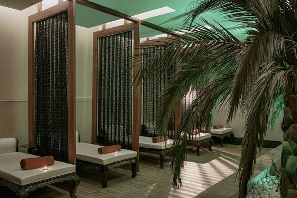Spa-Behandlungsraum im Delphin Imperial Hotel mit weißen Liegen und grünen Vorhängen.