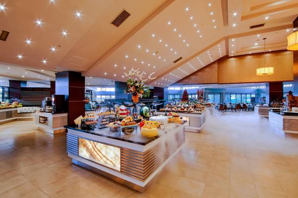 Innenansicht des Restaurants im Limak Lara De Luxe Hotel & Resort mit verschiedenen Essenstheken und gedimmten Lichtern.