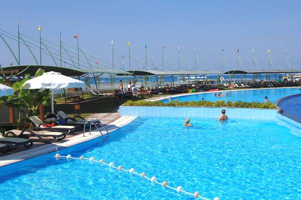 Außenpools des Limak Lara De Luxe Hotel & Resort mit Sonnenliegen und Flaggen