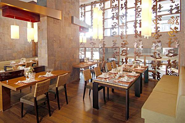 Restaurant-Innenraum des Limak Lara De Luxe Hotel mit Holztischen, Stühlen und Wanddekoration.