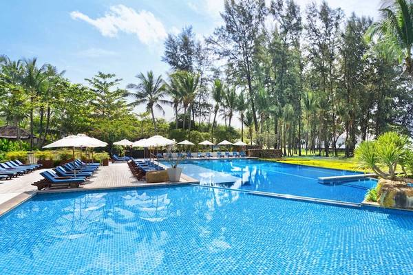 Außenpool des Dusit Thani Krabi Beach Resort mit Lounge-Stühlen, Sonnenschirmen und Blick auf das Meer.