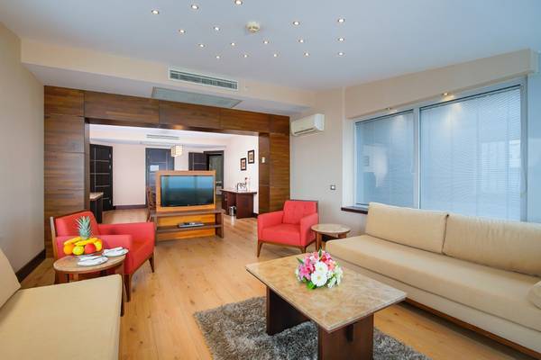 Hotelsuite Wohnzimmer mit Fernseher, Sofas, Esstisch und Früchten auf einem Tisch
