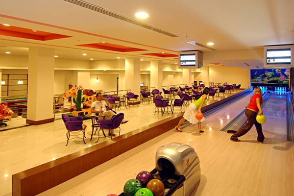 Innenansicht der Bowling-Halle im Limak Lara De Luxe Hotel & Resort mit Gästen und Bowlingbahnen.