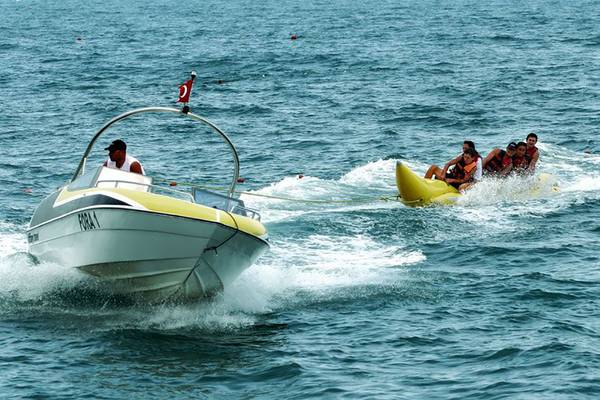 Ein Boot zieht ein Banana Boat mit mehreren Personen im Meer.
