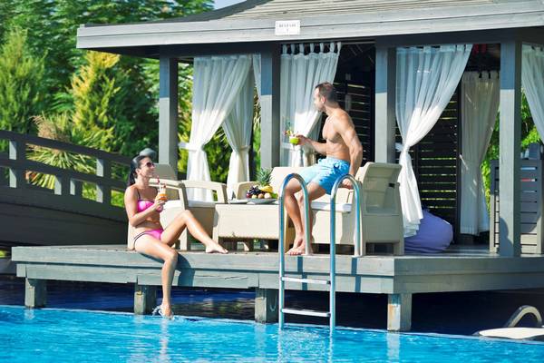 Paar sitzt auf einer Terrasse neben einem Pool mit Früchten und Getränken.
