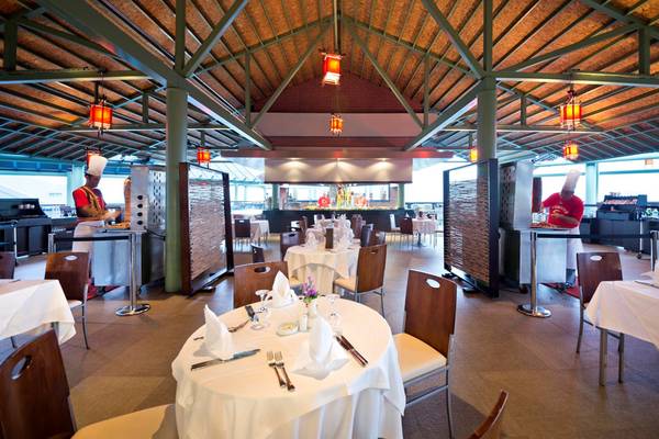 Innenbereich des Restaurants im Limak Lara De Luxe Hotel & Resort mit gedeckten Tischen und Köchen in Aktion.