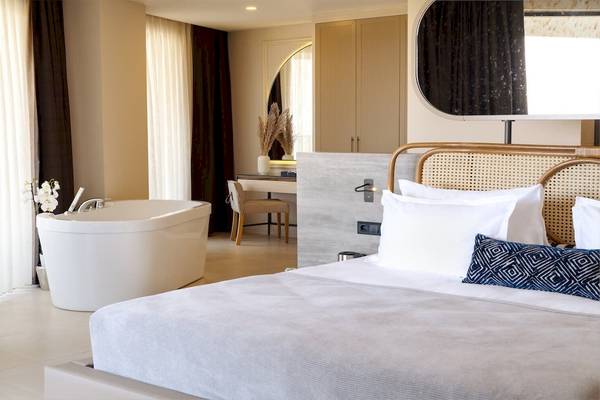 Schlafzimmer mit Badewanne im Liu Resorts mit minimalistischem Design, hellen Wänden und einem großen Bett.