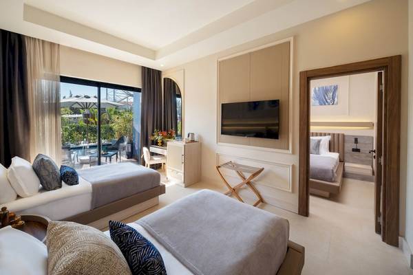 Innenansicht eines Doppelzimmers im Liu Resorts mit zwei Betten, Fernseher, Schreibtisch und einem Ausblick auf den Pool.