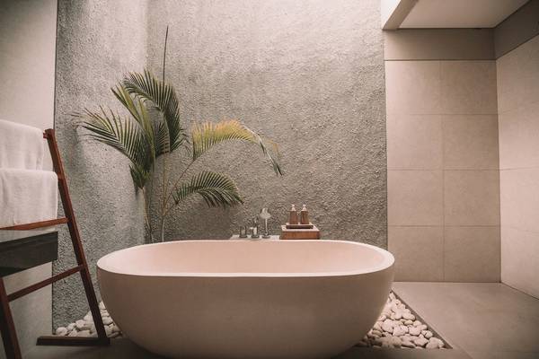Ein Badezimmer mit einer runden Badewanne, einer Palme und einem Holzständer mit Handtüchern.