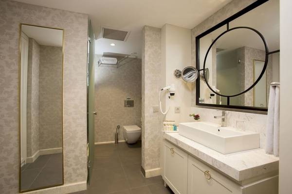 Badezimmer des Fame Residence Kemer & Spa mit Dusche, Toilette und Waschbecken.