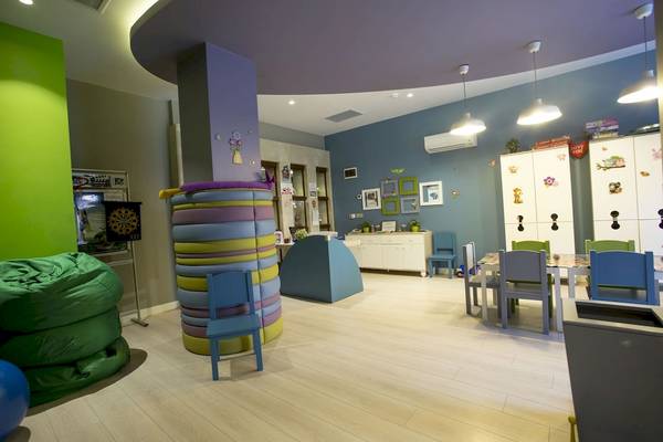 Ein farbenfrohes Kinderzimmer im Fame Residence Kemer & Spa mit bunten Stühlen, einer großen Sitzsäule und einem Essbereich.