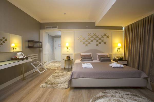 Schlafzimmer der Fame Residence Kemer mit Doppelbett, Nachttischen und Wandkunst.