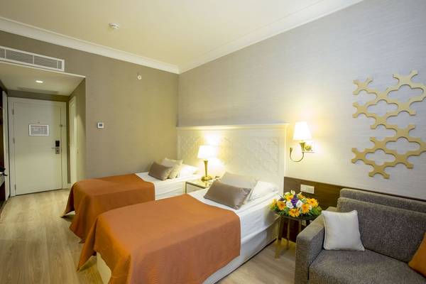 Suite-Zimmer im Fame Residence Kemer & Spa mit zwei Betten, Nachttischen, Lampen und einer Couch.