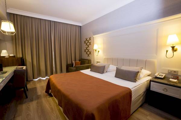 Foto eines eleganten Hotelzimmers mit einem Doppelbett, Nachttischen und Wandlampen.